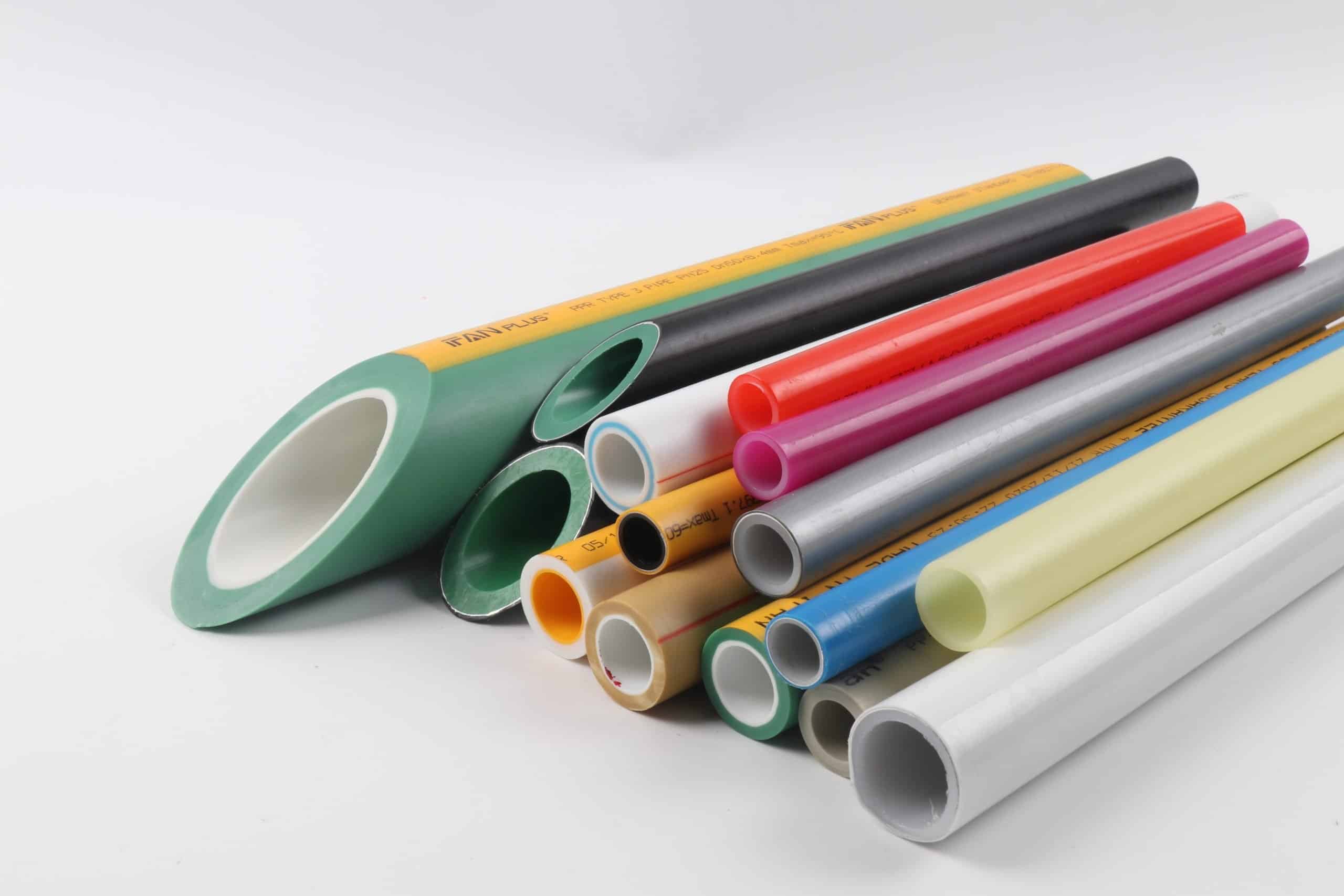 Cut sample lengths of pipe in several materials and colours, including green PP-R, showing wall cross-sections and printed marking strings