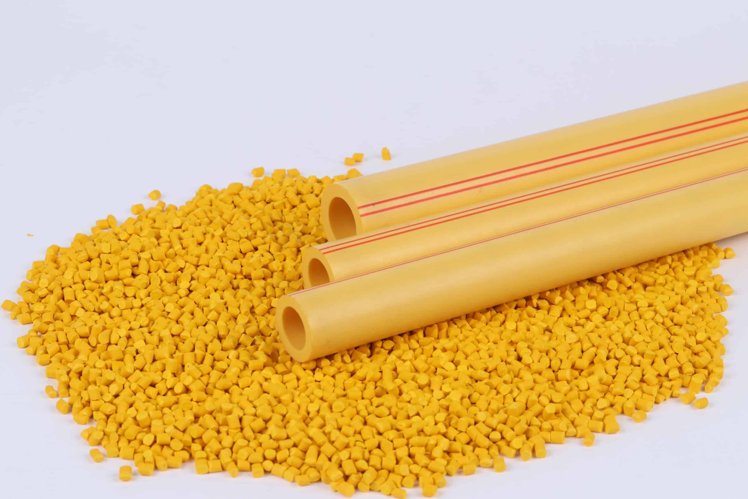 Cut PP-R pipe sections resting on coloured resin granules, showing the wall thickness that separates one SDR class from another
