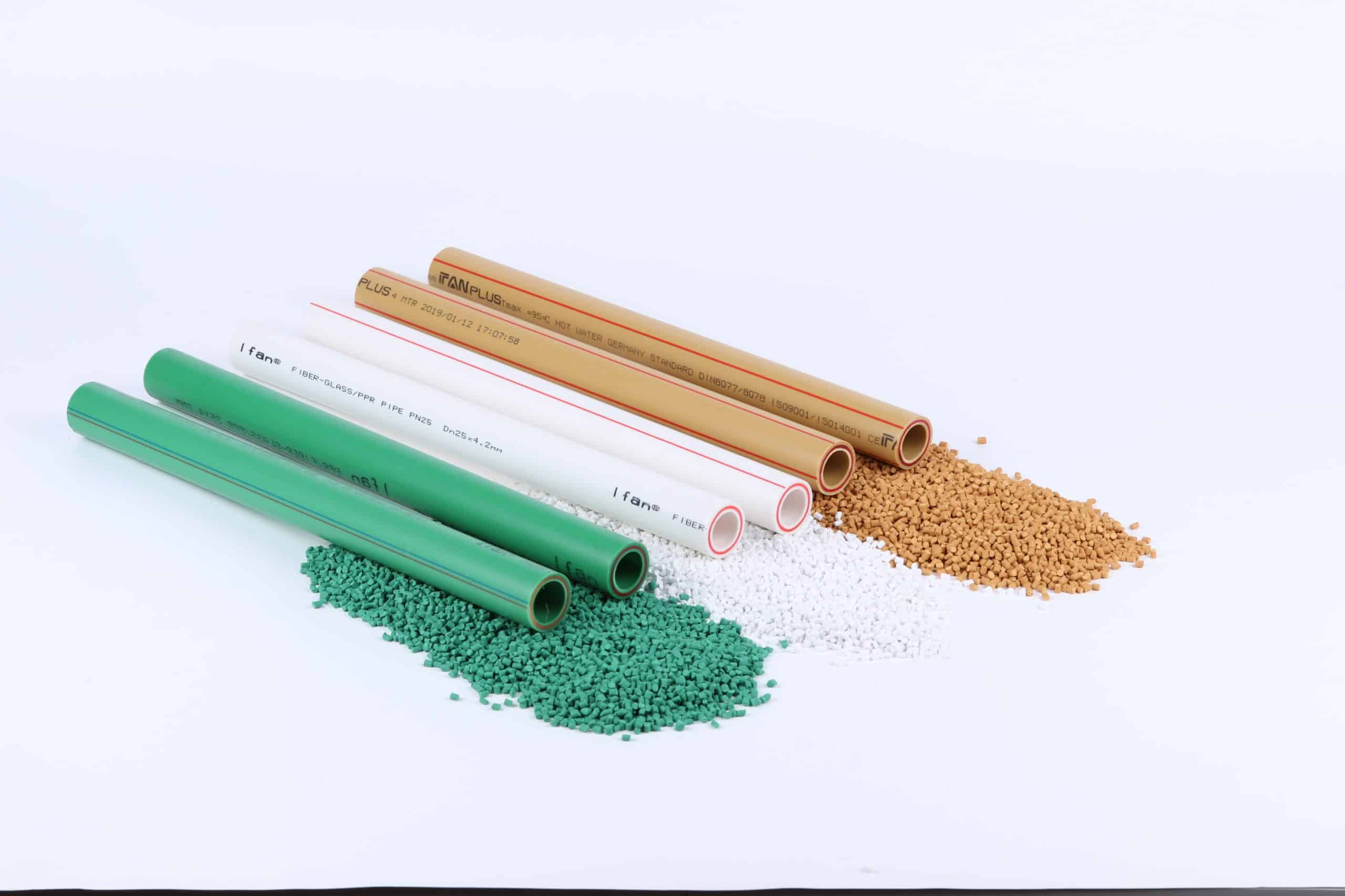 Green, white and orange-brown polypropylene pipes lying beside heaps of matching coloured polypropylene granules