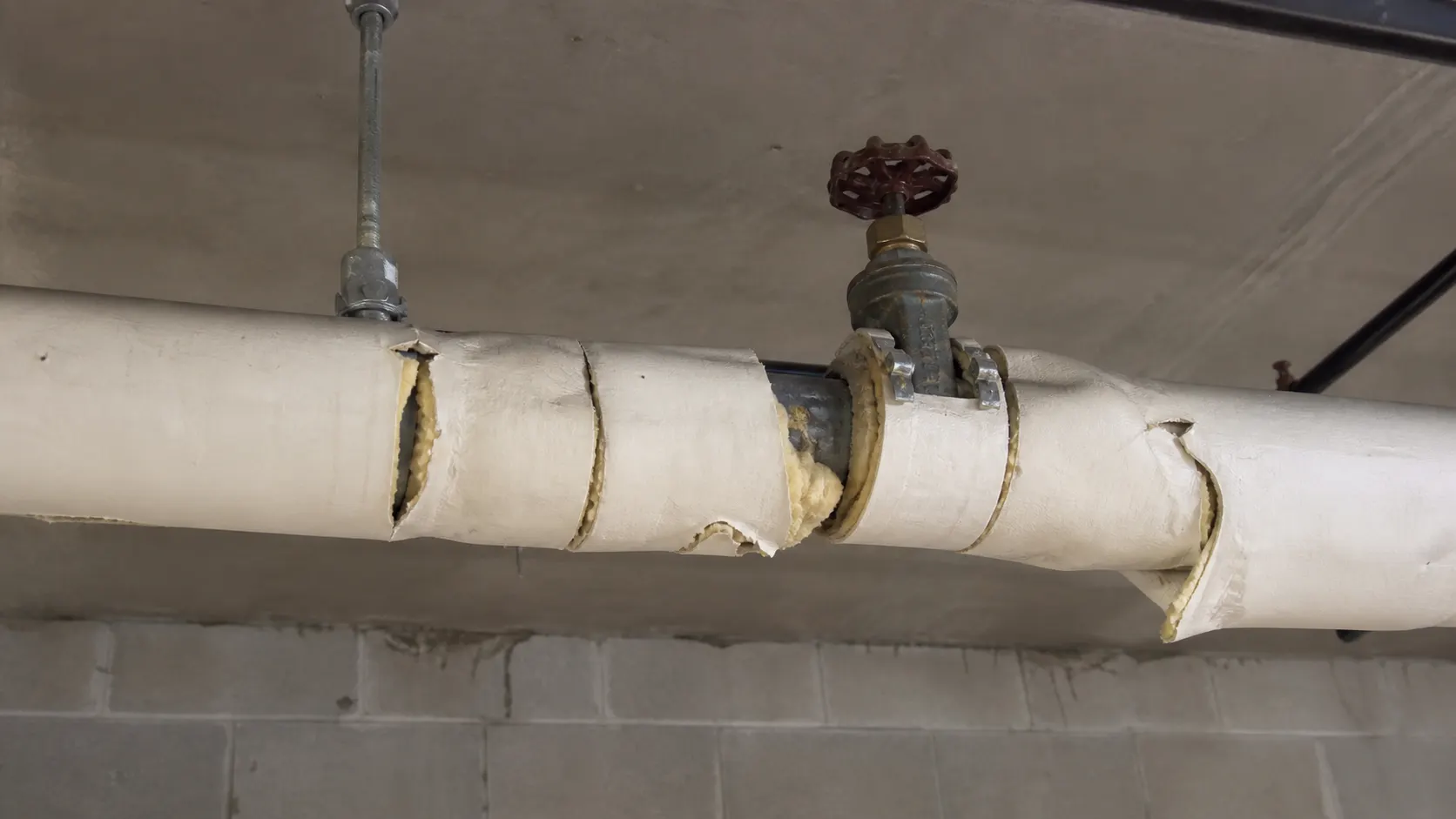 Badly insulated pipe run with unsealed seams, bare valve and exposed hanger highlighted