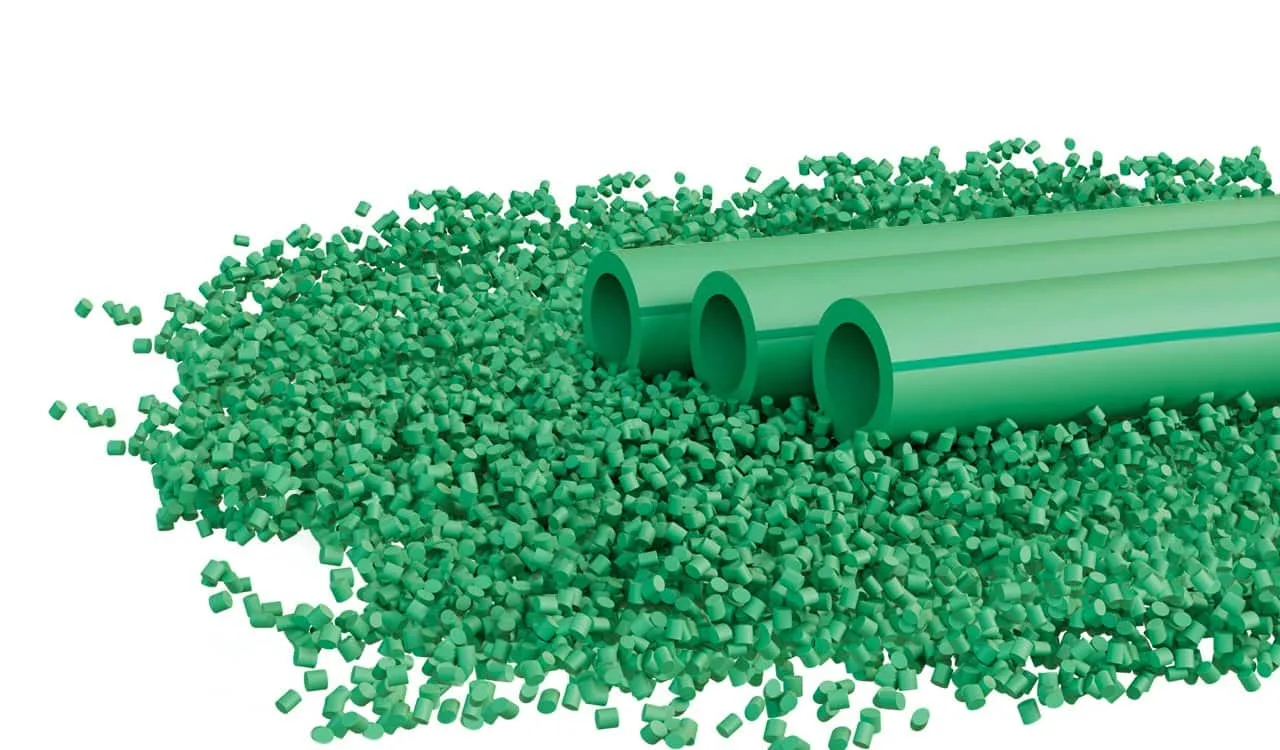 Three green pipe lengths resting on a pile of green polymer granules.