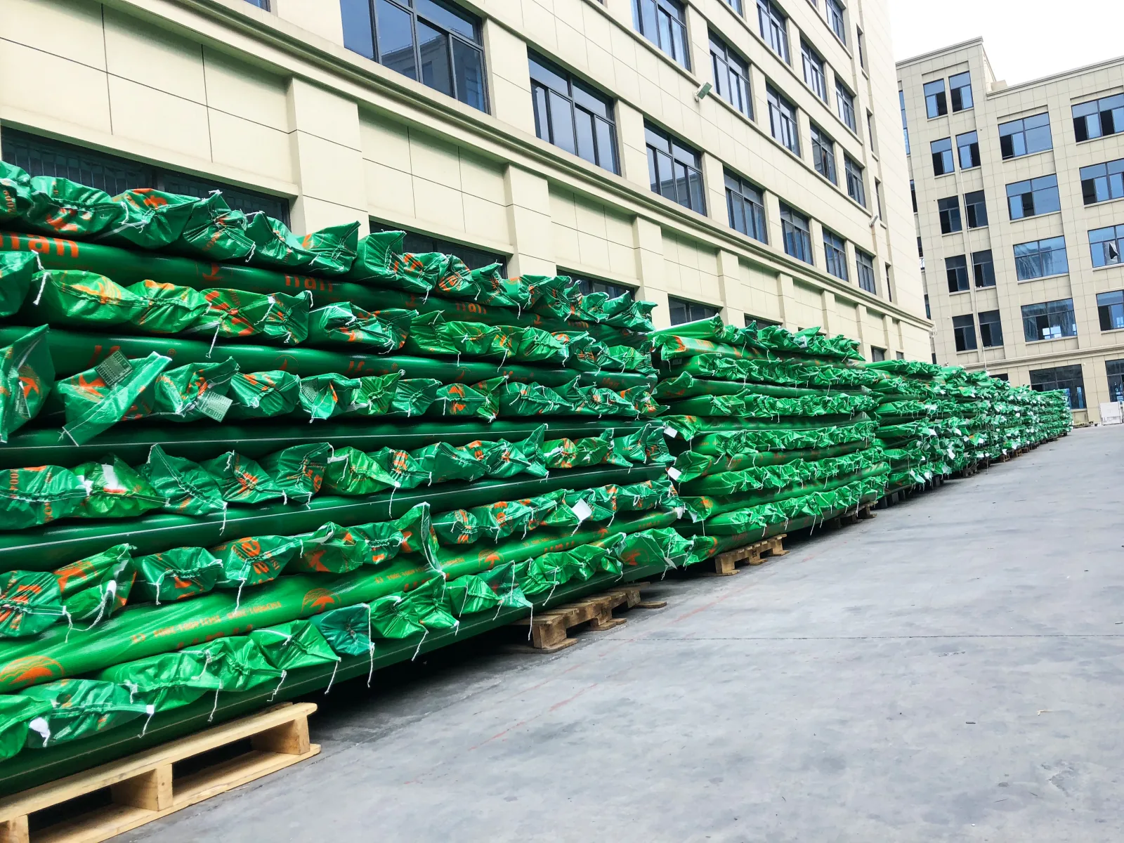 IFAN wrapped green pipe bundles stacked on pallets outside the factory